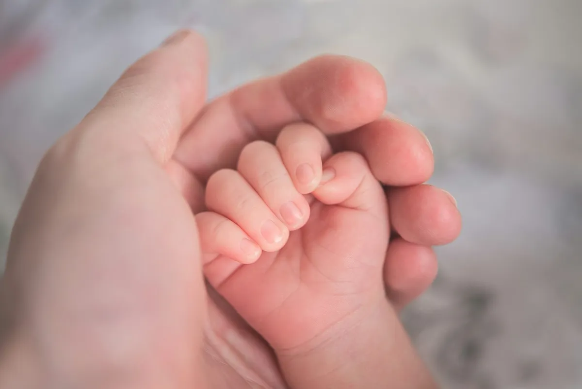 มือผู้ใหญ่ประคองมือทารก