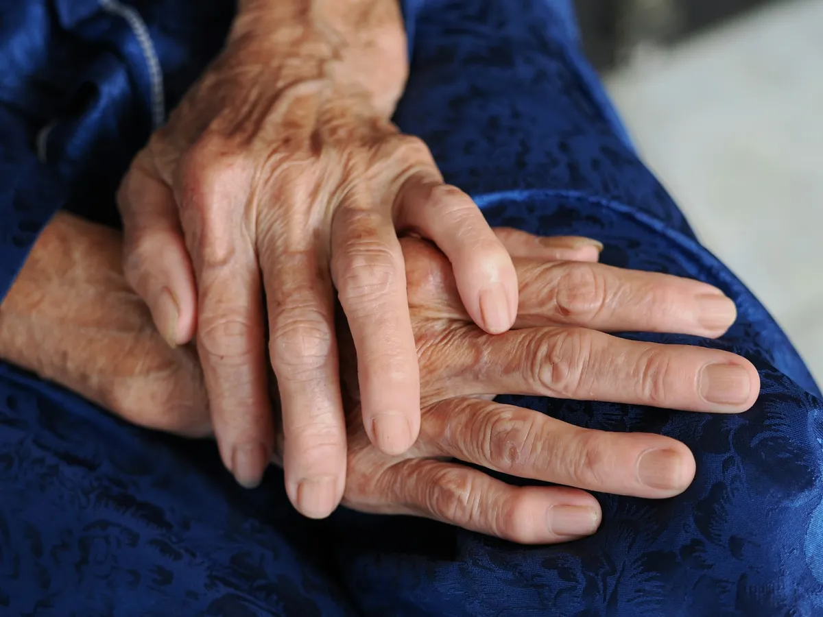 มือผู้สูงอายุวางบนผ้าสีฟ้า
